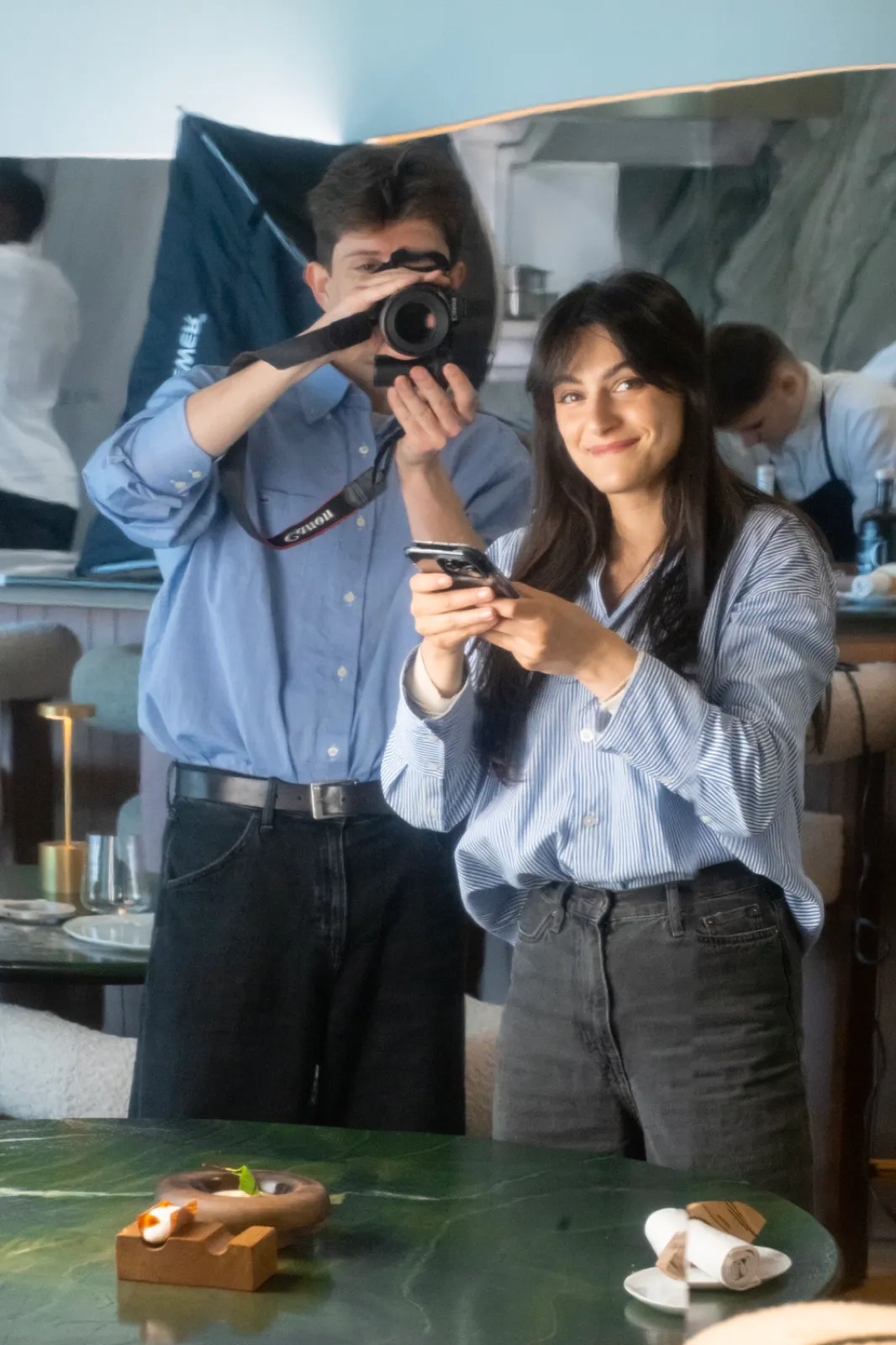 Manon et William en shooting au restaurant : lui photographie un plat, elle le filme au téléphone