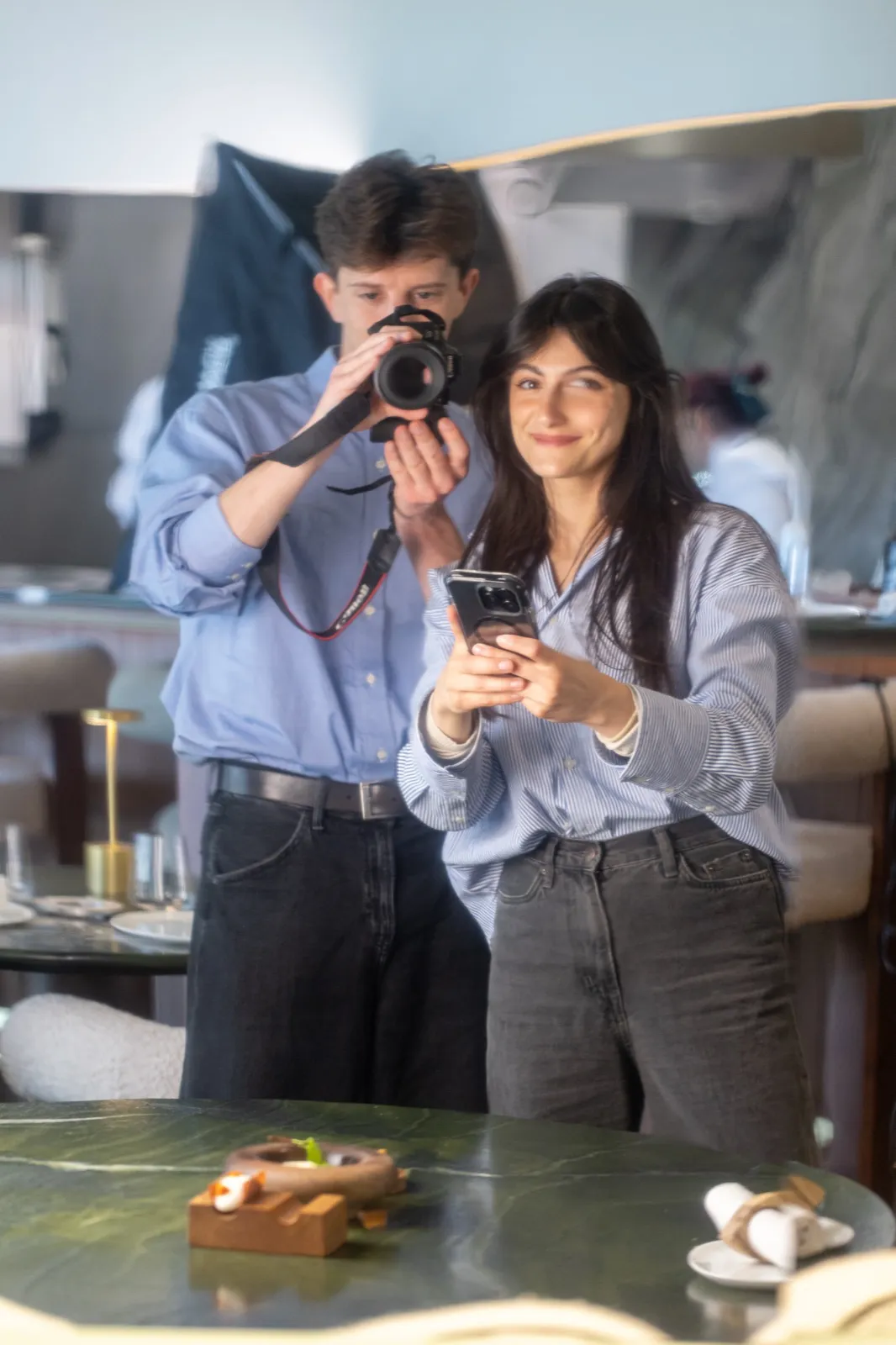 Manon et William en shooting au restaurant, appareil photo et téléphone en main