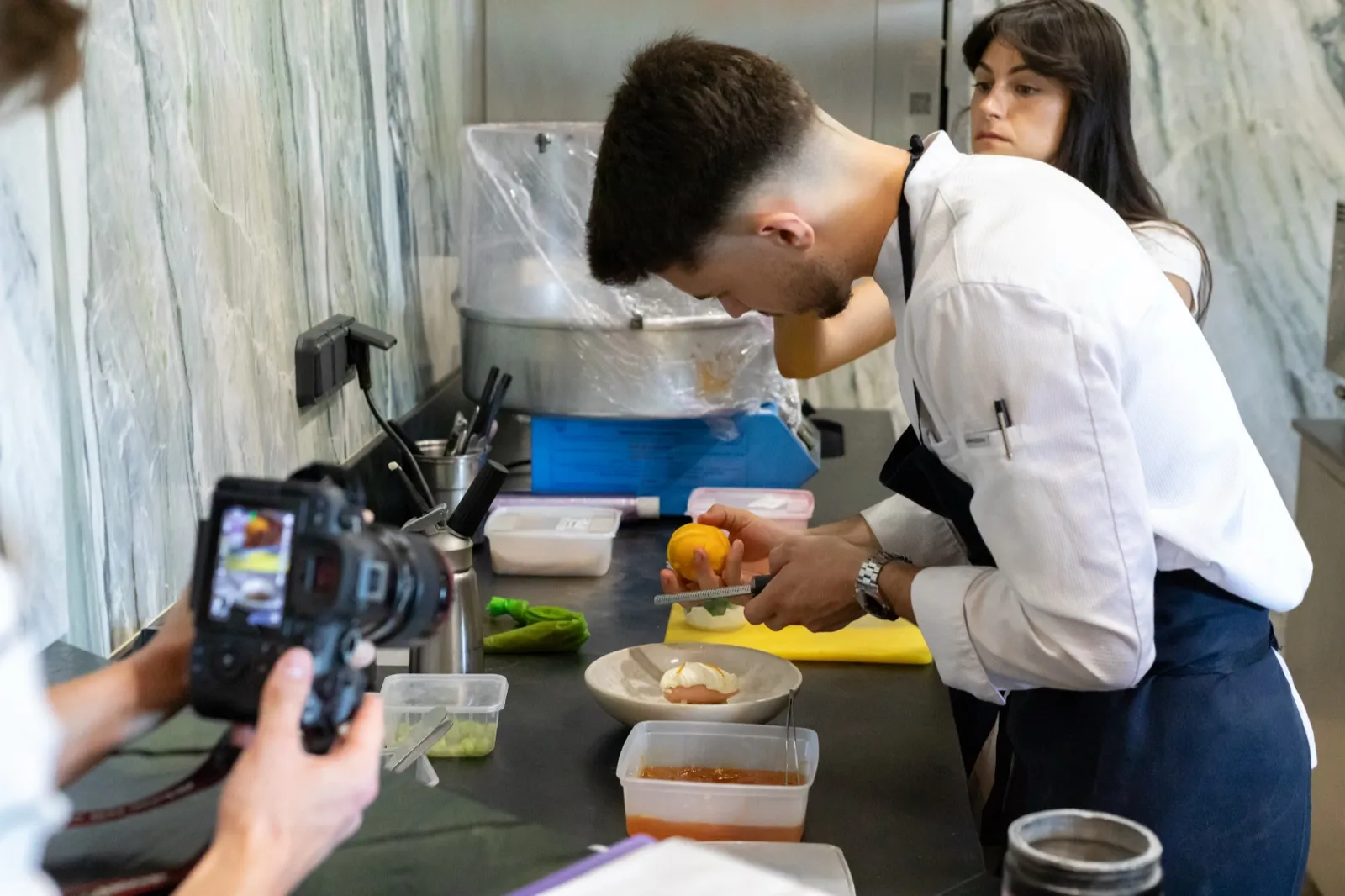 William filme un chef en cuisine pendant que Manon suit la prise