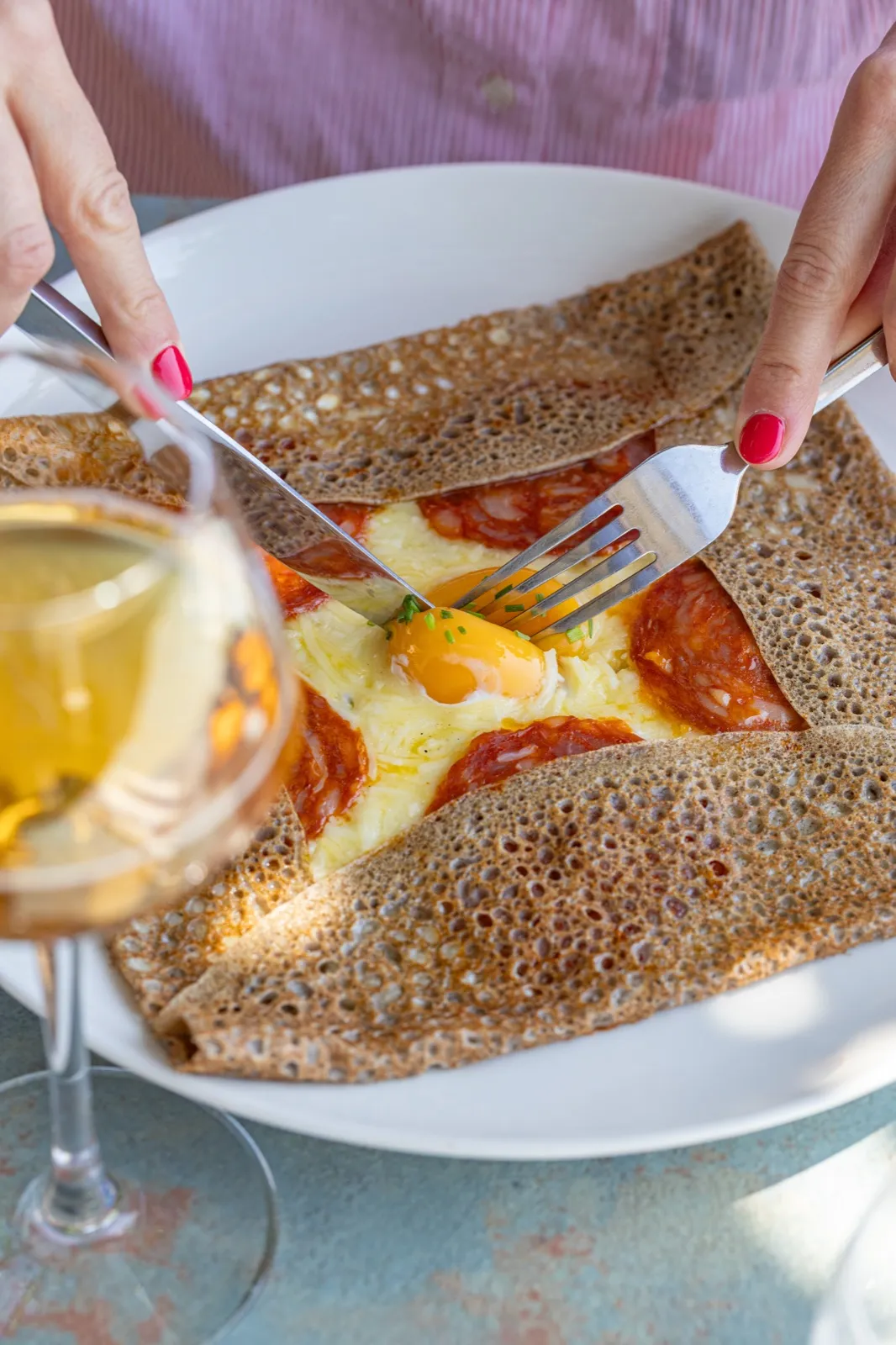 Une galette complète coupée à la fourchette, un verre de cidre