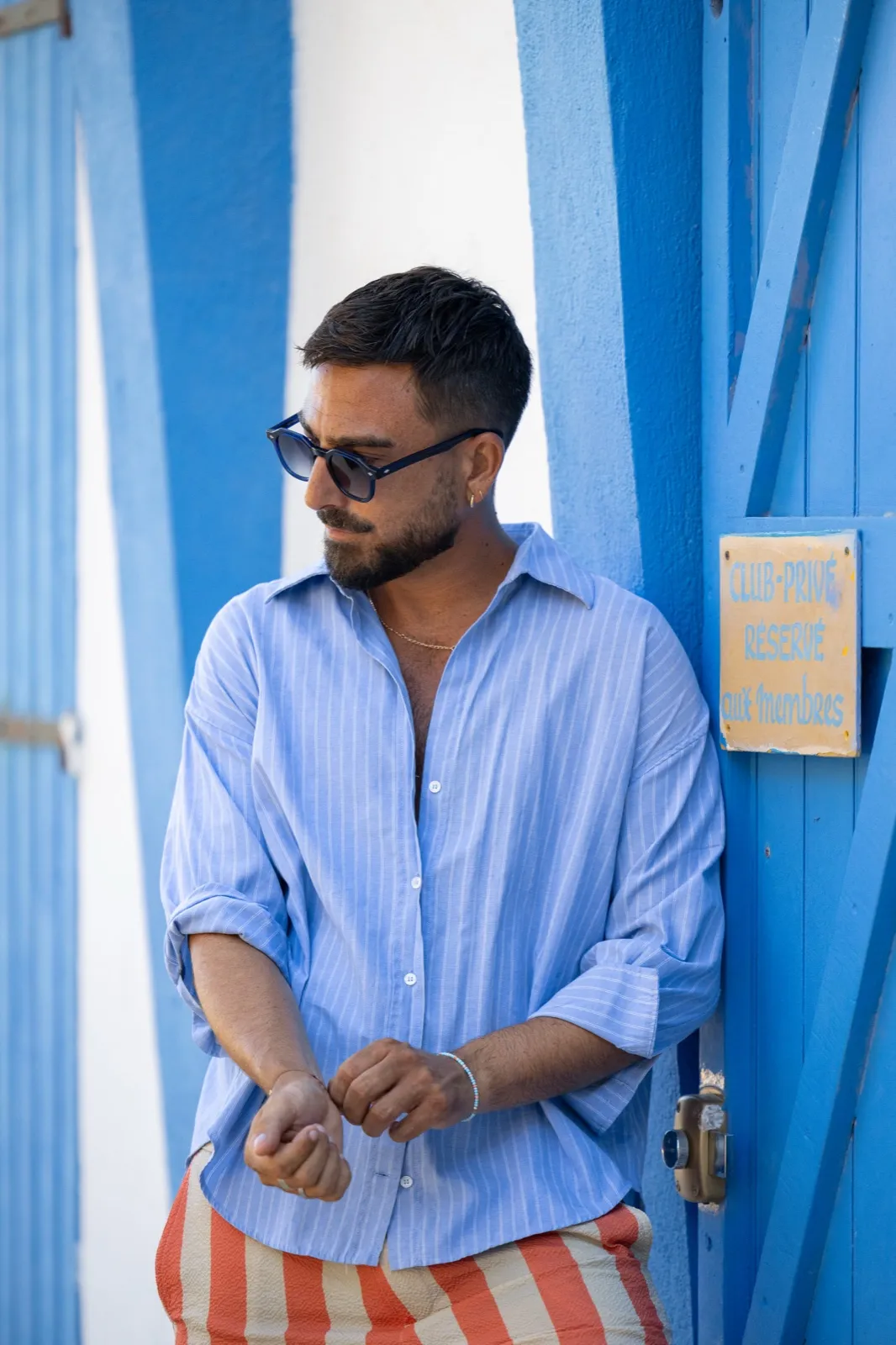 Portrait en lunettes de soleil devant une porte bleue